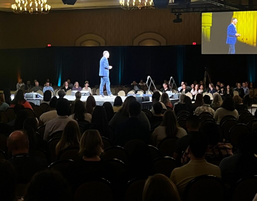 Chris Dyer on stage delivering a keynote to a full ballroom at a Siemens USA event
