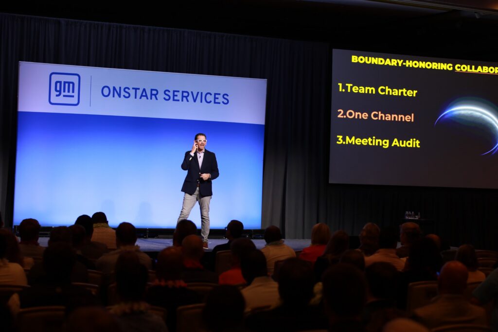 Chris Dyer on stage at GM OnStar Services teaching boundary-honoring collaboration: team charter, one channel, meeting audit
